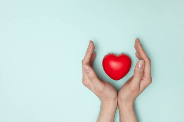 Здоровье, медицина и благотворительность - крупным планом женские руки с маленьким красным сердцем. Плоский лежал.
