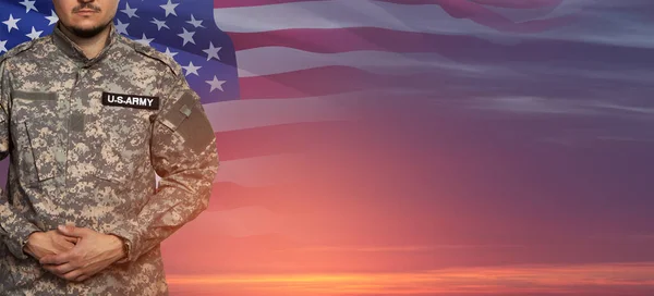 USA soldier in uniform on sunset sky background with USA flag. Memorial Day or Veterans day concept.