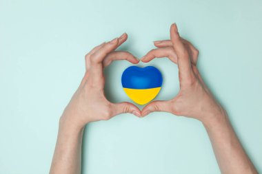 Heart with print the national flag of ukraine in female hand. Flat lay. Copy space.