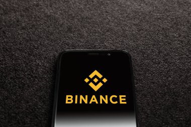 Smartphone with Binance logo on black textured background. Binance is a cryptocurrency exchange. Moscow, Russia - November 1, 2022.