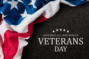 Closeup of American flag with Text Veterans Day Honoring All Who Served on black textured background. American holiday banner.