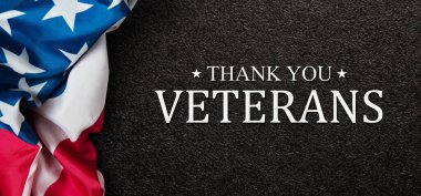 Closeup of American flag with Text Thank You Veterans on black textured background. American holiday banner.