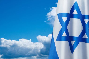 Israel flag with a star of David over cloudy sky background. Patriotic concept about Israel with national state symbols. Banner with place for text.