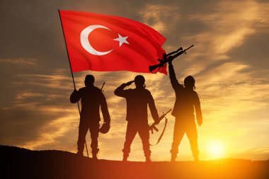 Silhouettes of soldiers with Turkey flag against the sunrise or sunset. Concept of crisis of war and conflicts between nations. Greeting card for Turkish Armed Forces Day, Victory Day.