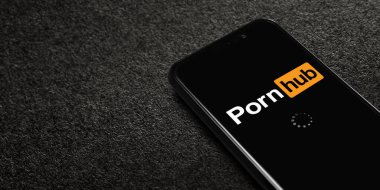 Siyah desenli arka planda Pornhub logosu olan akıllı telefon. Pornhub, pornografik video paylaşım ve porno sitesidir. Moskova, Rusya - 21 Şubat 2022.