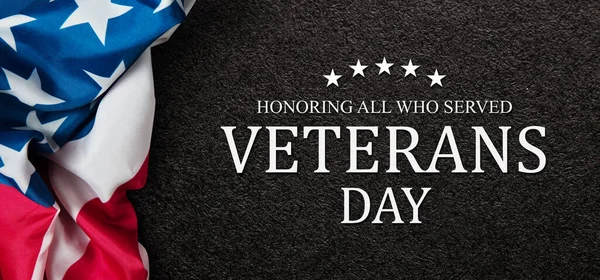 stock image Closeup of American flag with Text Veterans Day Honoring All Who Served on black textured background. American holiday banner.