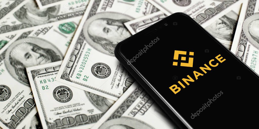 Smartphone with Binance logo on background of dollars. Binance is a cryptocurrency exchange. Moscow, Russia - November 1, 2022.