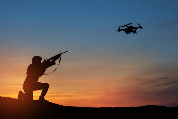 夕日を背景に偵察ドローンを撃墜しようとする兵士 兵士は四辺形を撃つ 戦争の近代的な方法 技術コンセプト — ストック写真