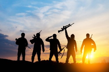 Silhouettes of soldiers standing against the backdrop of a sunset. Greeting card for Veterans Day, Memorial Day, Independence Day. USA celebration. Concept - patriotism, protection, remember honor.