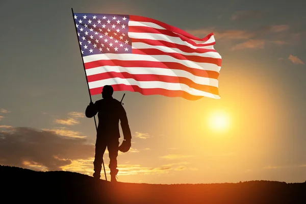 stock image Silhouettes of soldier with USA flag against the backdrop of a sunset. Greeting card for Veterans Day, Memorial Day, Independence Day. USA celebration. Patriotism, protection, remember honor.