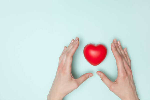 Здоровье, медицина и благотворительность - крупным планом женские руки с маленьким красным сердцем. Плоский лежал.