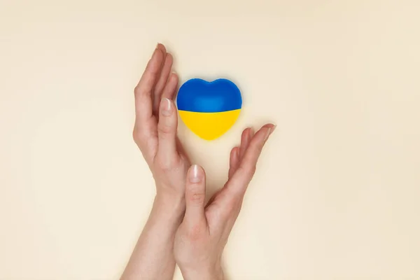 stock image Heart with print the national flag of ukraine in female hands. Flat lay. Copy space.