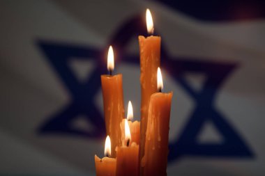 Six burning candles on Israel flag background. International Holocaust Remembrance Day, January 27.