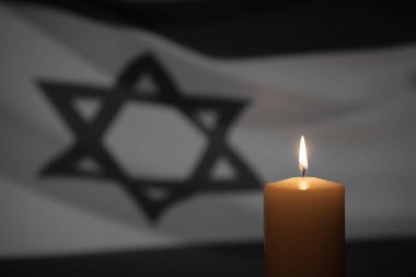 Burning candle on Israel flag background. International Holocaust Remembrance Day, January 27.