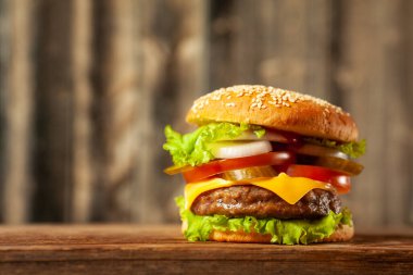 Eski ahşap arka planda, ahşap masada taze, lezzetli etsiz hamburger. Boşluğu kopyala.