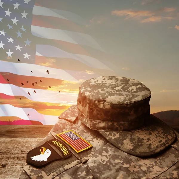アメリカの国旗と空を飛ぶ鳥と日没の空の背景に古い木製のテーブルの上に記章とアメリカ軍の制服 記念日又は退役軍人の日の概念 — ストック写真