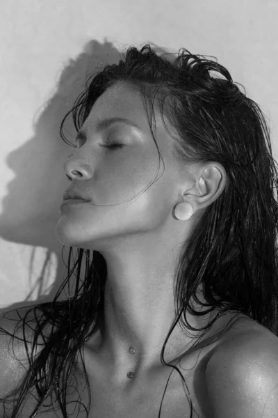 Close-up portrait of beautiful woman\'s purity face. Model with wet clean shiny skin. Small drops on the skin. Black and white photo.