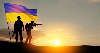 Flag of Ukraine with silhouette of soldiers against the sunrise or sunset. Concept - armed forces of Ukraine. Relationship between Ukraine and Russia.