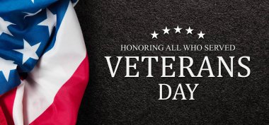 Closeup of American flag with Text Veterans Day Honoring All Who Served on black textured background. American holiday banner.