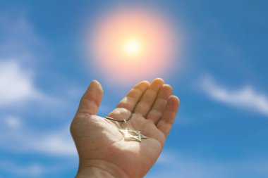 Closeup of pendant in the shape of the star of david on the hand of a man on blue sky background. Holocaust remembrance day.