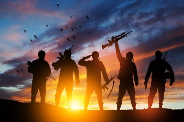 Silhouettes of soldiers standing against the backdrop of a sunset. Greeting card for Veterans Day, Memorial Day, Independence Day. USA celebration. Concept - patriotism, protection, remember honor.