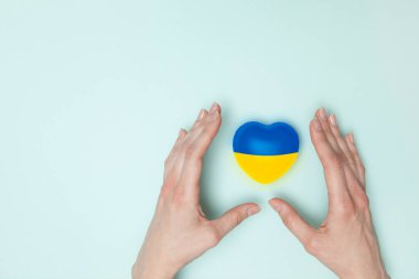 Heart with print the national flag of ukraine in female hand. Flat lay. Copy space.