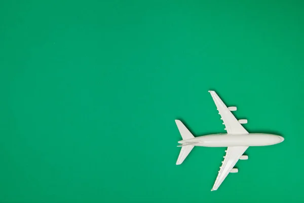 Airplane model. White plane on green background. Travel vacation concept. Summer background. Flat lay, top view, copy space.