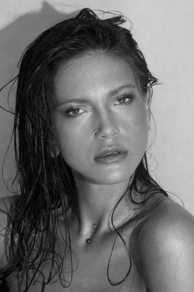 Close-up portrait of beautiful woman\'s purity face. Model with wet clean shiny skin. Small drops on the skin. Black and white photo.