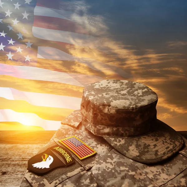 USA military uniform with insignias on old wooden table on sunset sky background with USA flag. Memorial Day or Veterans day concept.