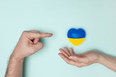 Ukrayna 'nın ulusal bayrağını kadının elinde ve kalbi işaret eden adamın elinde bastır. Düz yatıyordu. Boşluğu kopyala.