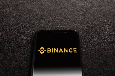 Smartphone with Binance logo on black textured background. Binance is a cryptocurrency exchange. Moscow, Russia - November 1, 2022.