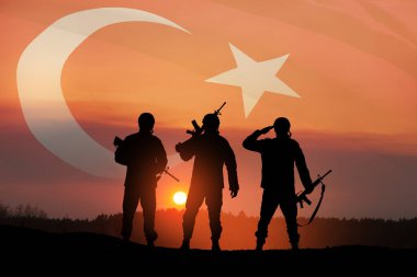 Silhouettes of soldiers on a background of Turkey flag and the sunset or the sunrise. Concept of crisis of war and conflicts between nations. Greeting card for Turkish Armed Forces Day, Victory Day.