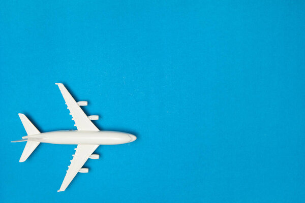 Airplane model. White plane on blue background. Travel vacation concept. Summer background. Flat lay, top view, copy space.