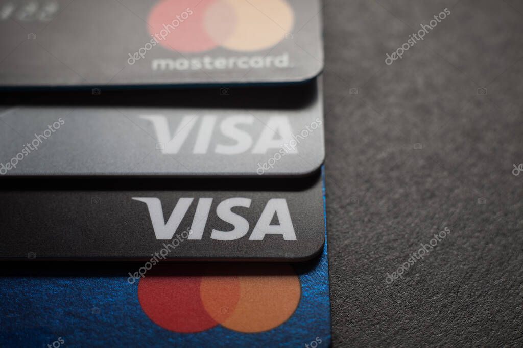 Close-up of Visa credit cards and Mastercard credit cards placed on a dark background. Macro photo. Moscow, Russia - March 14, 2022.