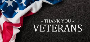 Closeup of American flag with Text Thank You Veterans on black textured background. American holiday banner.