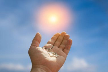 Closeup of pendant in the shape of the star of david on the hand of a man on blue sky background. Holocaust remembrance day.