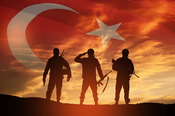 Silhouettes of soldiers on a background of Turkey flag and the sunset or the sunrise. Concept of crisis of war and conflicts between nations. Greeting card for Turkish Armed Forces Day, Victory Day.