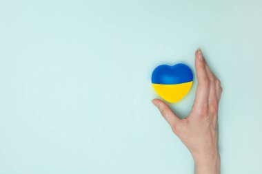 Heart with print the national flag of ukraine in female hand. Flat lay. Copy space.
