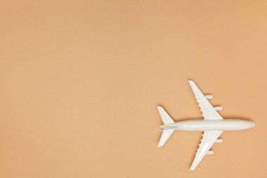 Uçak modeli. Açık kahverengi arka planda beyaz bir uçak. Seyahat tatili konsepti. Yaz dönemi. Düz konum, üst görünüm, kopyalama alanı.