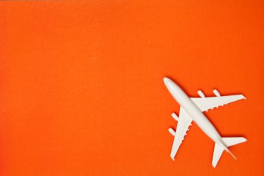 Airplane model. White plane on orange background. Travel vacation concept. Summer background. Flat lay, top view, copy space.