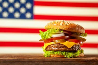 Yakın plan ev yapımı hamburgerler ahşap masada Amerikan bayraklı arka planda.