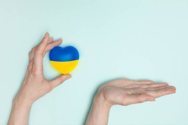 Ukrayna 'nın ulusal bayrağını kadın ellerine ve avuç içlerine bastıran bir kalp. Düz yatıyordu. Boşluğu kopyala.