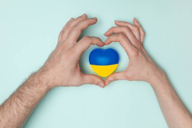 Ukrayna 'nın ulusal bayrağını kadın ve erkeğin ellerine basan kalp. Düz yatıyordu. Boşluğu kopyala.