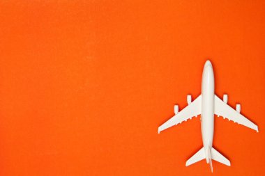 Airplane model. White plane on orange background. Travel vacation concept. Summer background. Flat lay, top view, copy space.