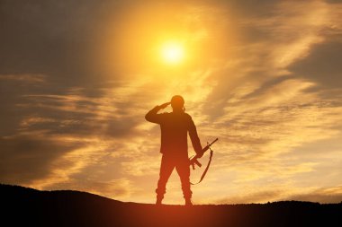 Silhouette of soldier standing against the backdrop of a sunset. Greeting card for Veterans Day, Memorial Day, Independence Day. USA celebration. Concept - patriotism, protection, remember honor.