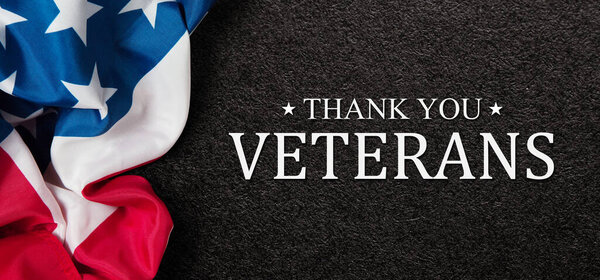 Closeup of American flag with Text Thank You Veterans on black textured background. American holiday banner.