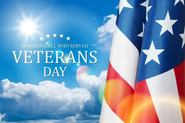 American flags with Text Veterans Day Honoring All Who Served on blue sky background. American holiday banner.