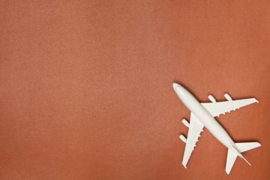 Uçak modeli. Kahverengi arka planda beyaz uçak. Seyahat tatili konsepti. Yaz dönemi. Düz konum, üst görünüm, kopyalama alanı.