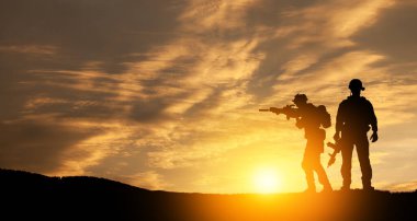 Silhouettes of soldiers standing against the backdrop of a sunset. Greeting card for Veterans Day, Memorial Day, Independence Day. USA celebration. Concept - patriotism, protection, remember honor.