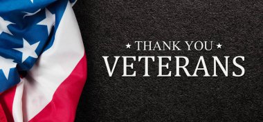 Closeup of American flag with Text Thank You Veterans on black textured background. American holiday banner.